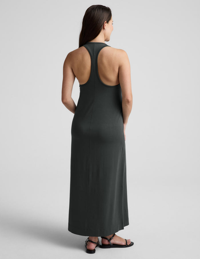 Woman wearing a dark green sleeveless dress on a light gray background.
