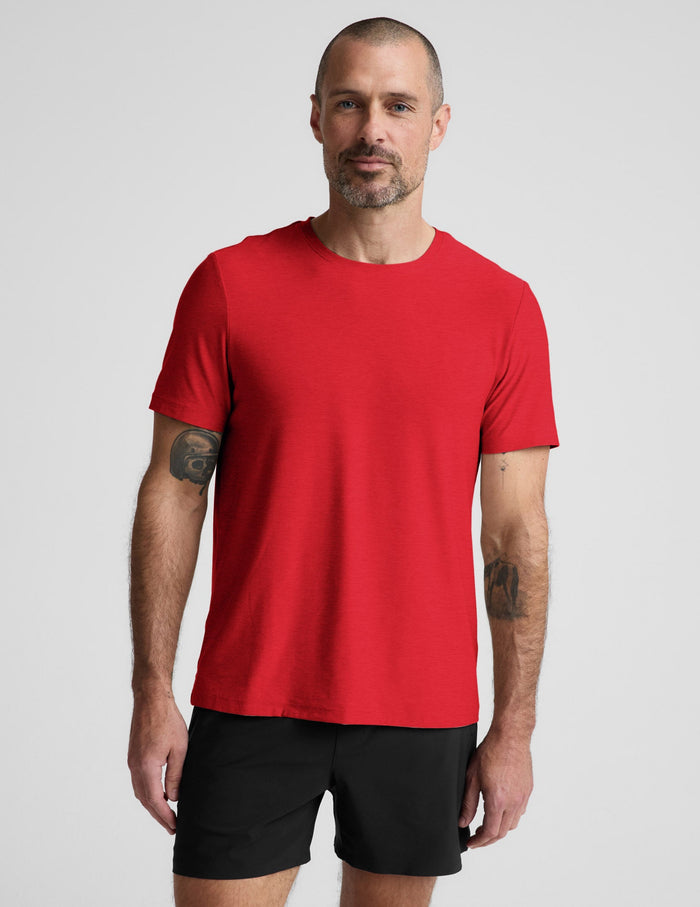 Man wearing a red t-shirt and black shorts on a light gray background