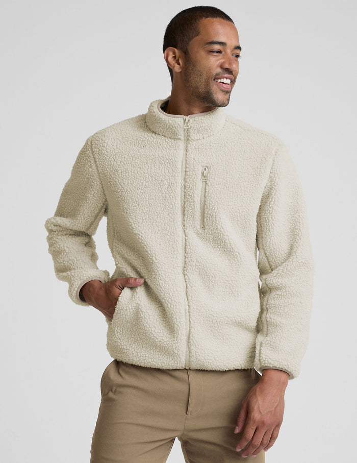 model wearing a men's beige fleece zip-up jacket on a plain background.