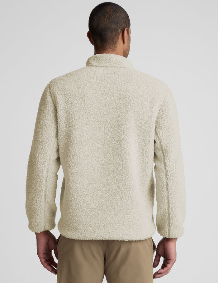 model wearing a men's beige fleece zip-up jacket on a plain background.