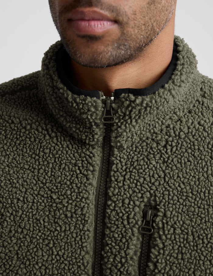 model wearing a men's green fleece zip-up jacket on a light gray background.