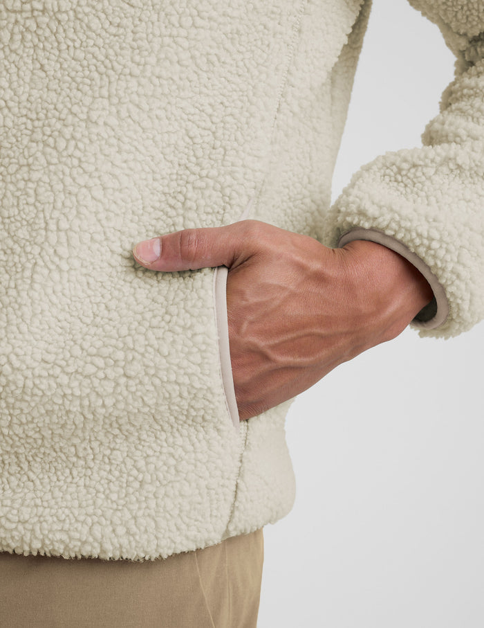 model wearing a men's beige fleece zip-up jacket on a plain background.