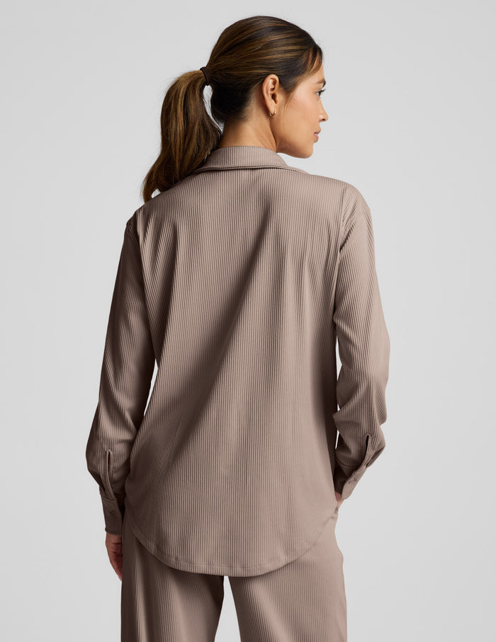 Woman wearing a brown corduroy button-up shirt and pants on a light gray background.