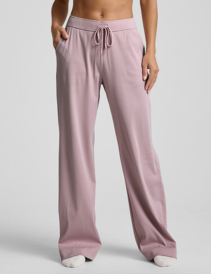 Pink corduroy lounge pants worn by a person on a light gray background.