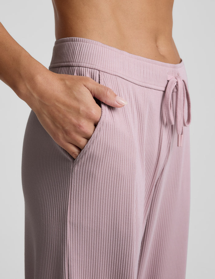 Pink corduroy lounge pants worn by a person on a light gray background.