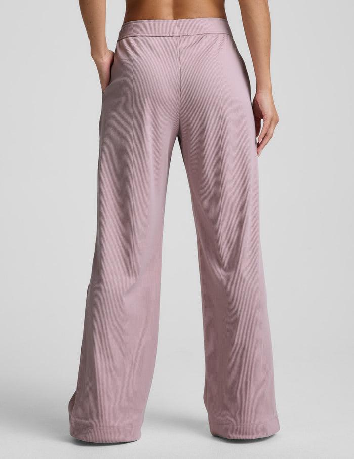 Pink corduroy lounge pants worn by a person on a light gray background.