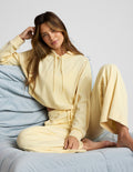 Woman wearing a yellow hoodie and pants sitting on a light blue couch.