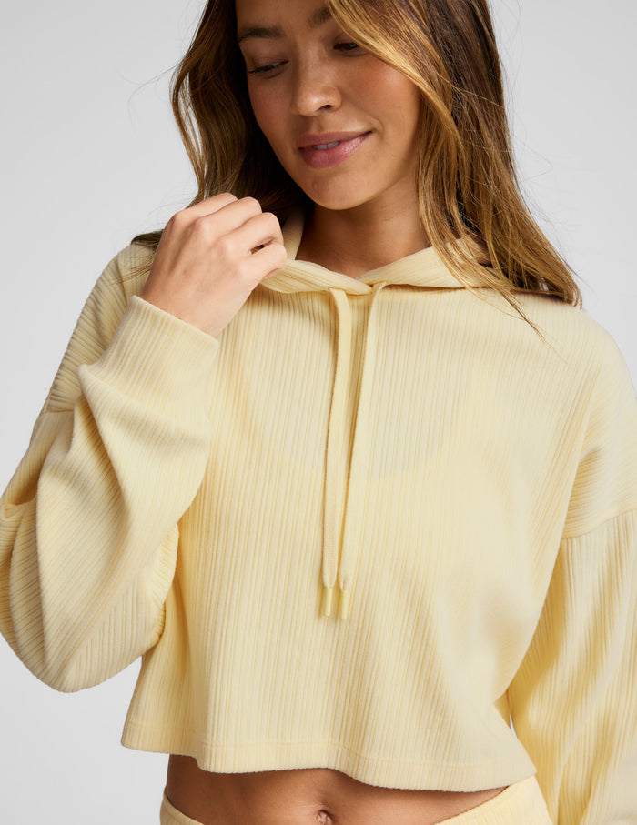 Woman wearing a light yellow hoodie against a plain background.