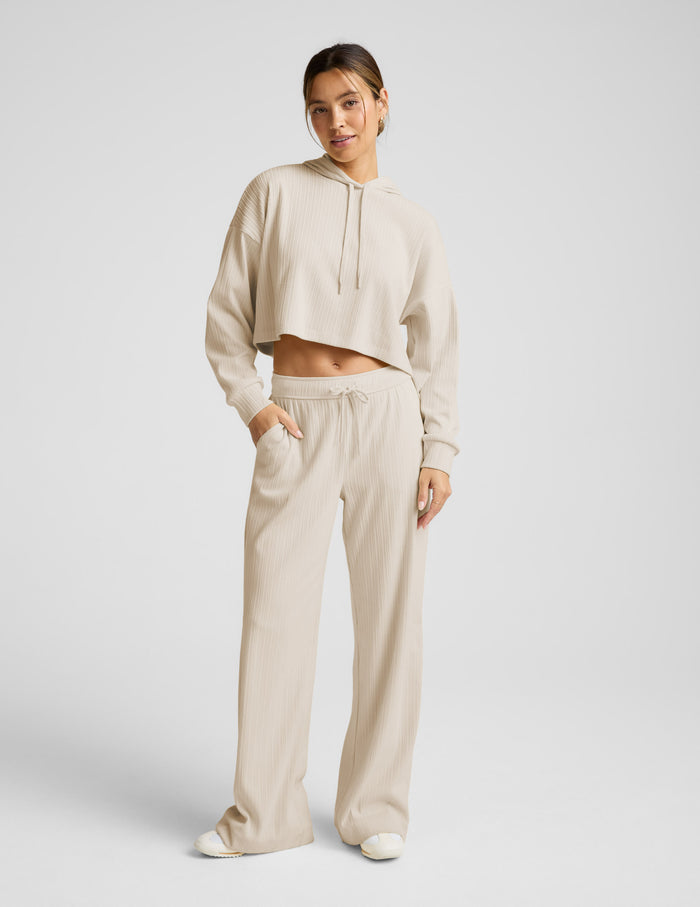 Cream Breathe Easy Ribbed Wide Leg Pant featuring vertical ribs, a drawstring waist, and side pockets on a smiling model.