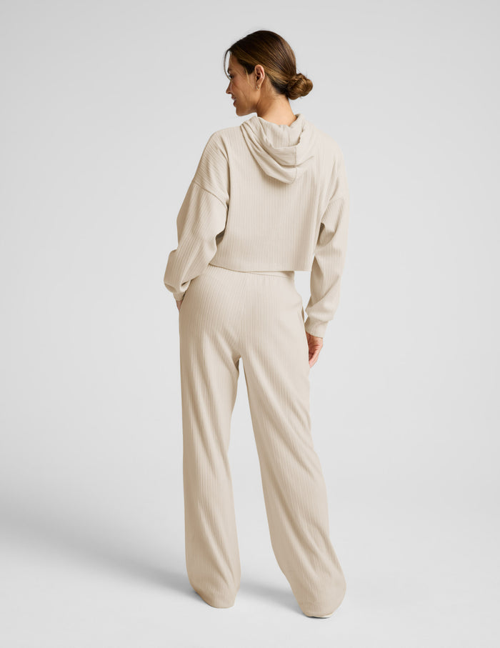 Rear view of model in cream Breathe Easy Ribbed Wide Leg Pant and matching hoodie, showing the long, wide-leg silhouette.