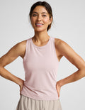 Woman wearing a pink sleeveless active tank and beige shorts against a plain background.