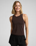 Woman wearing a brown tank top and black athletic shorts against a plain background.