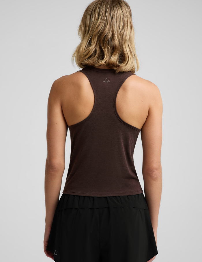 Woman wearing a brown tank top and black athletic shorts against a plain background.