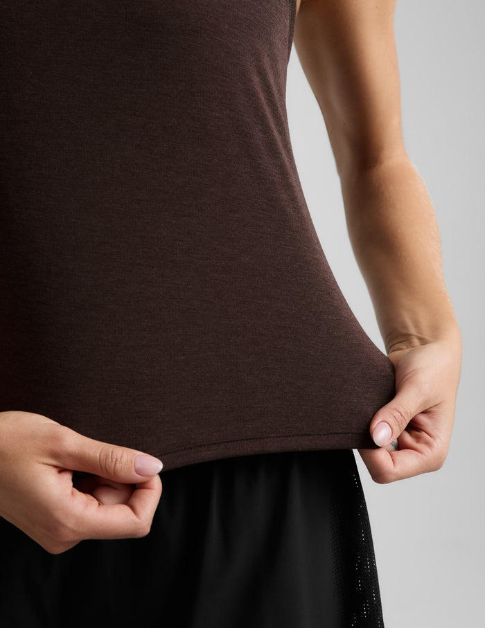 Woman wearing a brown tank top and black athletic shorts against a plain background.