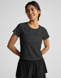 Woman wearing a dark gray t-shirt and black shorts on a light gray background.
