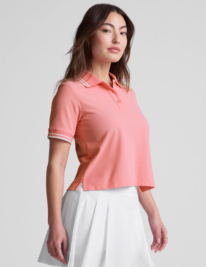 pink polo style top with a stripe rib collar and cuff , front placket with buttons, side slits, and hits at a high hip length.