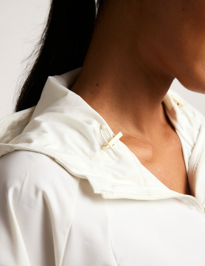 Close-up of a person wearing a white jacket with a blurred background.