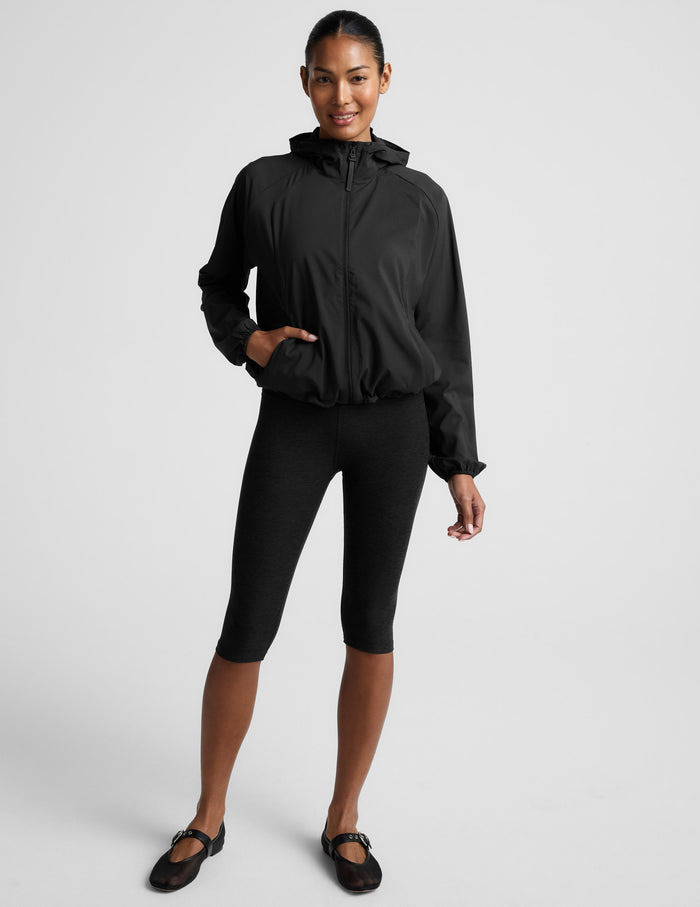 Woman wearing a black jacket and black leggings on a white background.