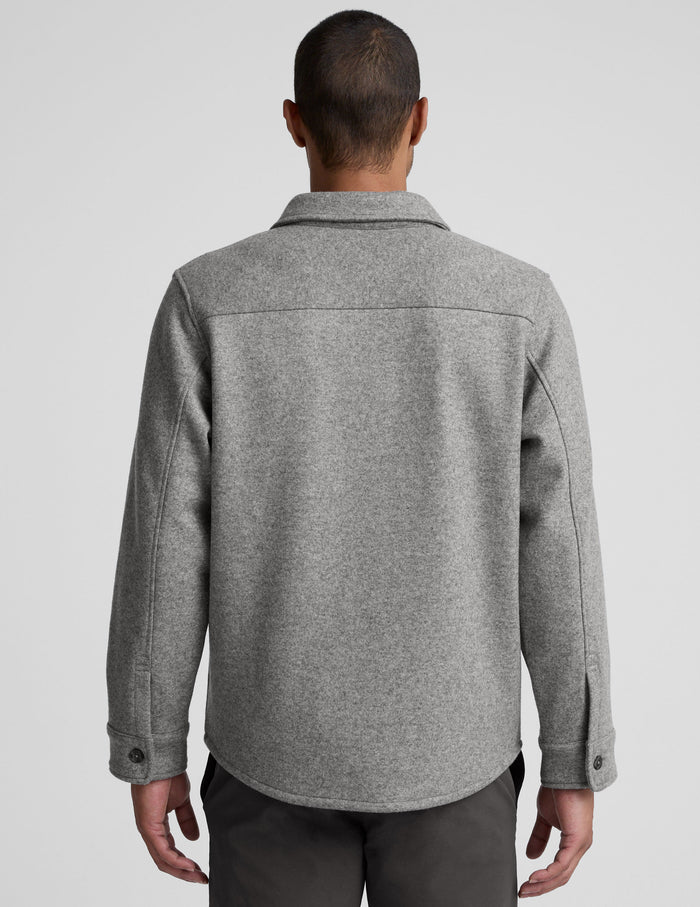 model wearing a gray men's button up jacket over a black shirt on a light gray background.