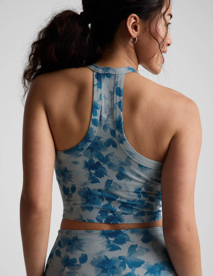 Woman wearing a blue floral sports bra and leggings on a light gray background.
