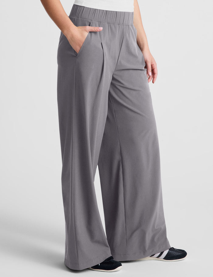 Gray Easy Wide Leg Pant on a model, featuring a relaxed flowy fit, elastic waistband, and side pockets with a pleated front.