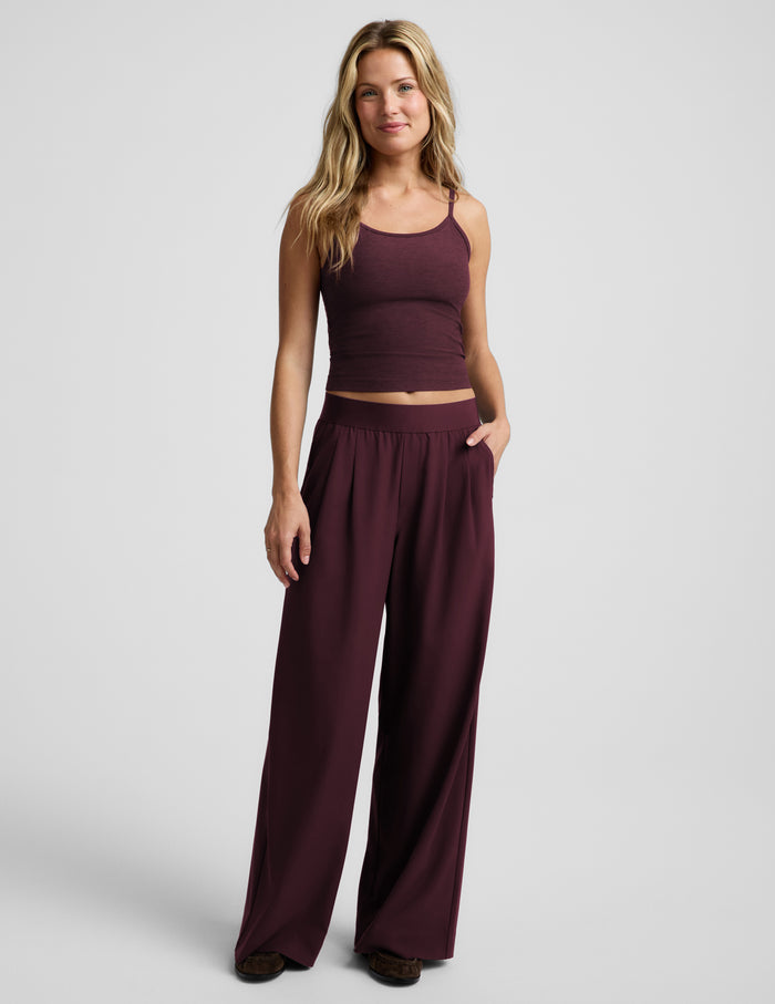 A woman modeling a matching two-piece set consisting of a dark burgundy tank top and wide-leg pants, photographed against a light gray studio background.