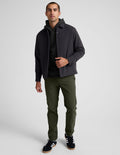 Man wears olive green Essential Men's Chino 30" Trouser with a straight-leg fit, black jacket, and sneakers.