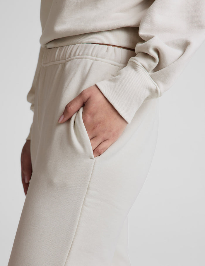 Woman wearing Cream Fade Out Mid-Rise Sweatpant™ with hand in slant pocket, paired with a matching cream sweatshirt.