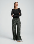 Smiling woman in Olive Faux Leather Pant featuring a wide leg, elasticated drawstring waistband, and side pockets.