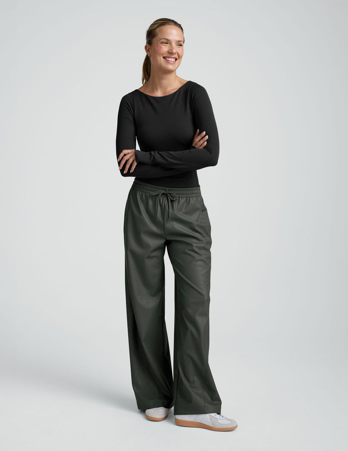 Smiling woman in Olive Faux Leather Pant featuring a wide leg, elasticated drawstring waistband, and side pockets.