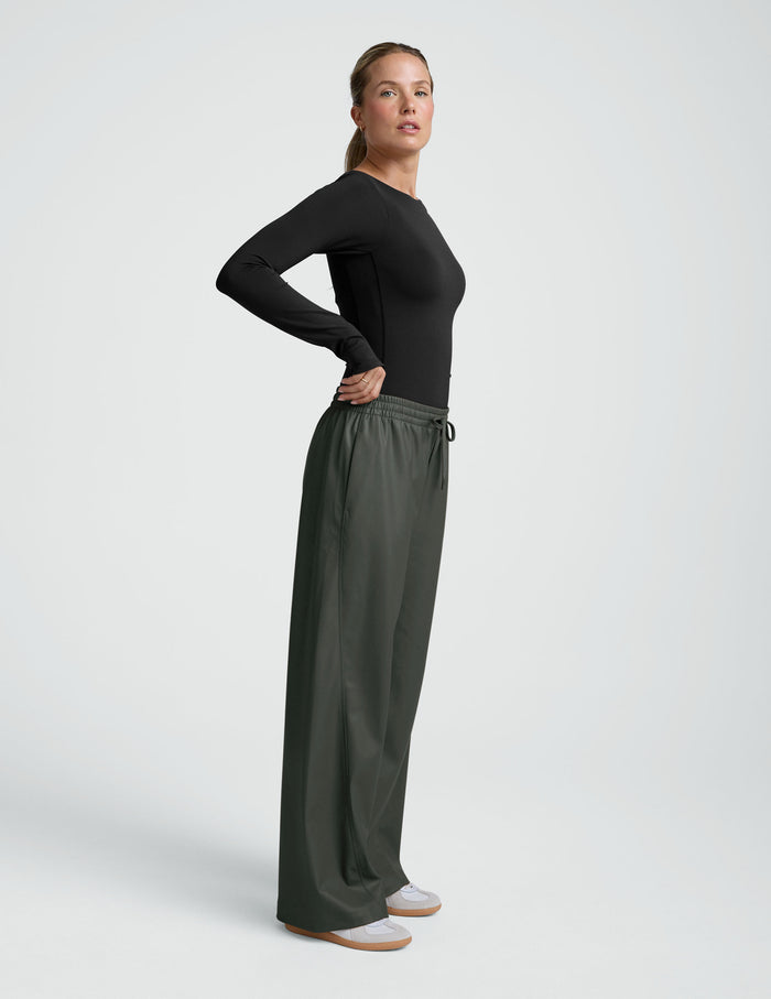 Side view of olive wide-leg Faux Leather Pant featuring a gathered elastic drawstring waistband and side pockets.
