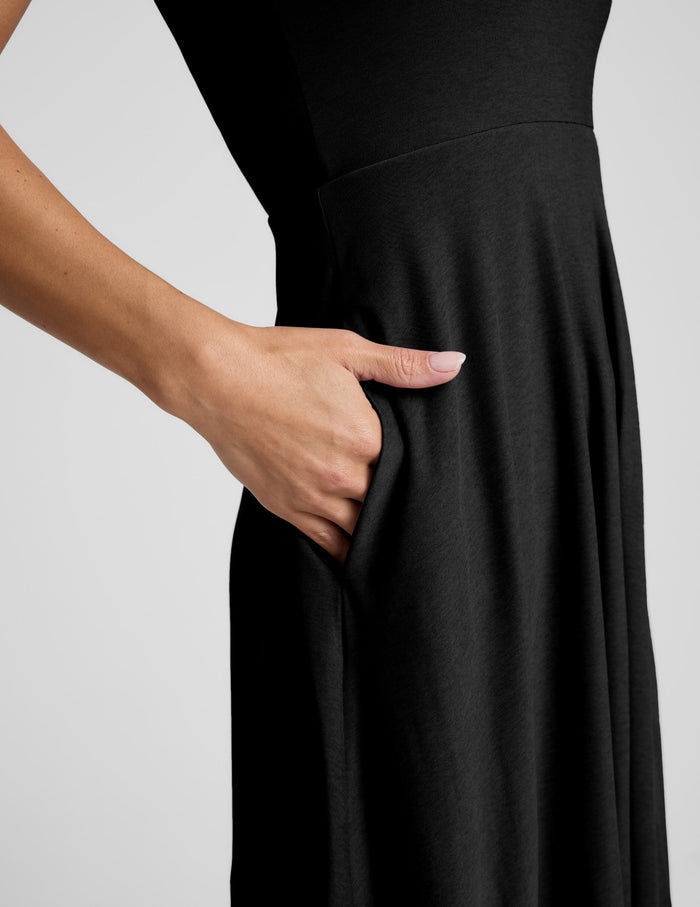 Woman wearing a black sleeveless dress on a white background.