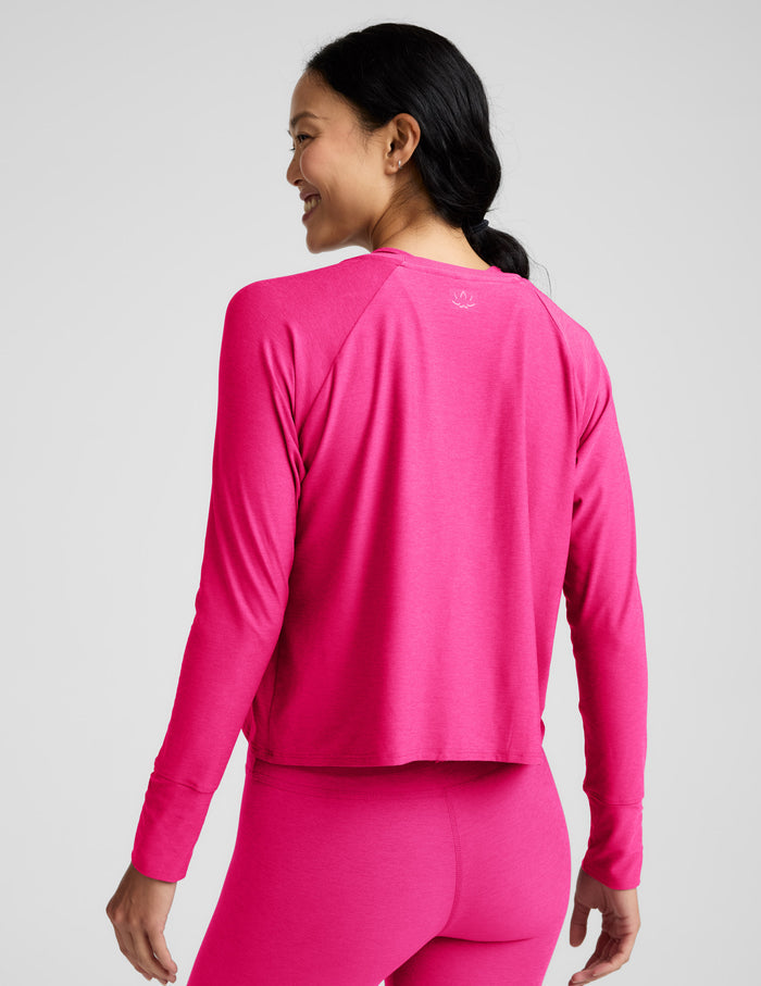 Woman wearing a bright pink long-sleeve top and leggings on a light gray background.