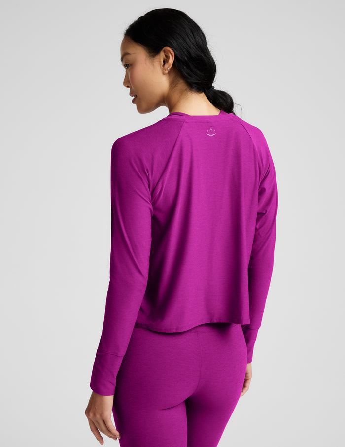 A woman modeling a matching magenta-purple long-sleeve top and leggings set against a solid light gray background.
