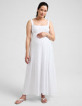 Pregnant woman wearing a white maxi dress against a plain background.