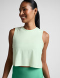 Woman wearing a light green sleeveless top and leggings against a plain background.