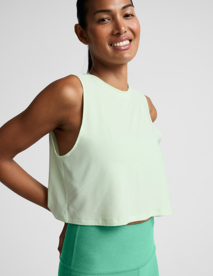 Woman wearing a light green sleeveless top and leggings against a plain background.