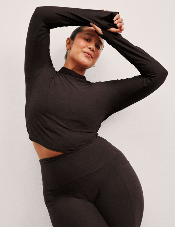 model wearing a brown mock neck cropped long sleeve against a plain background.