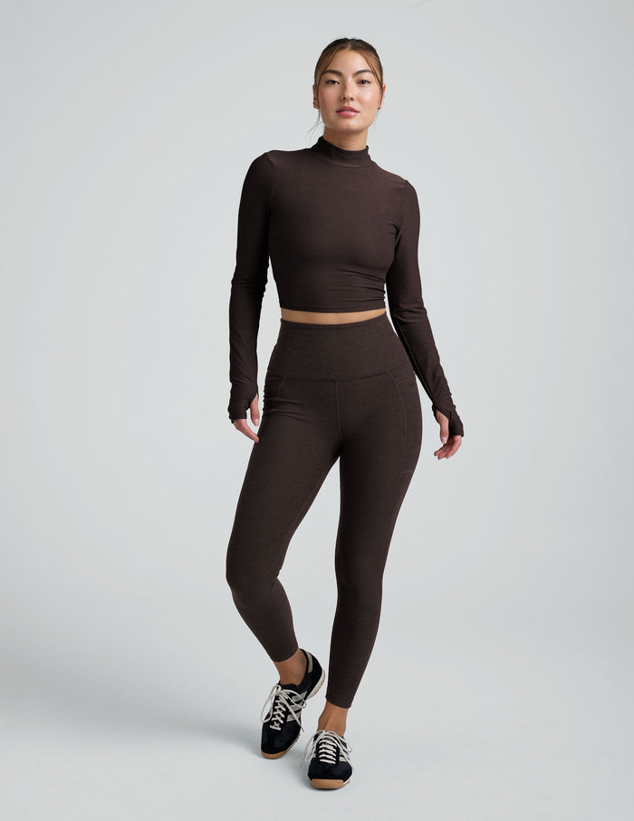 model wearing a brown mock neck cropped long sleeve against a plain background.