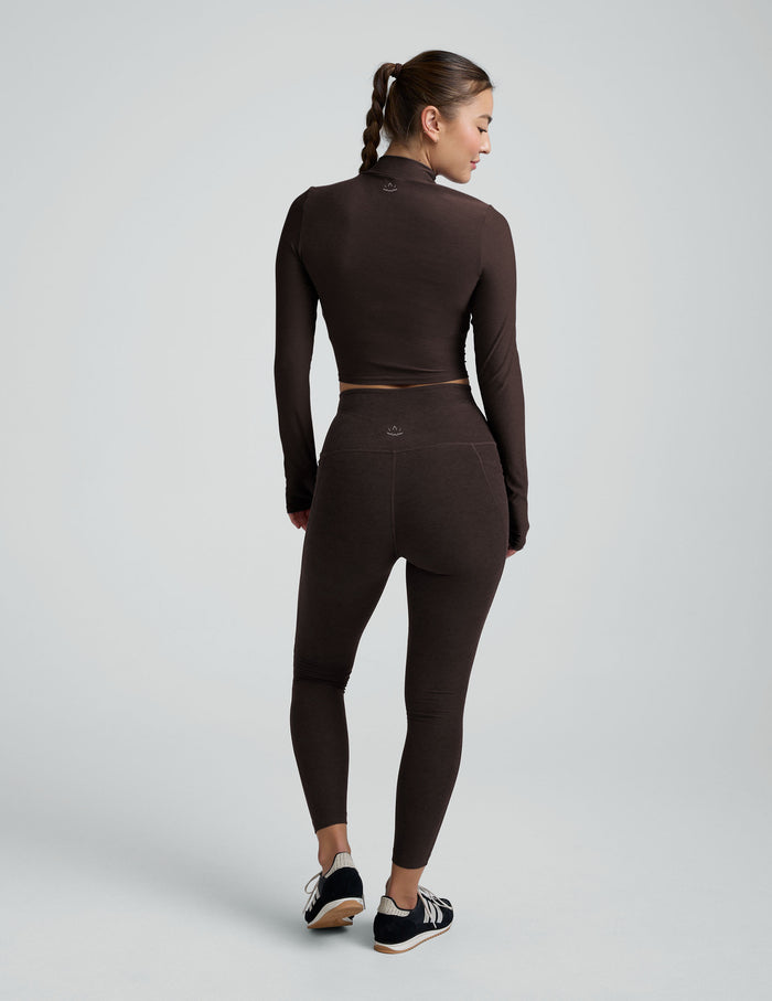 model wearing a brown mock neck cropped long sleeve against a plain background.