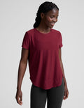 Woman wearing a red t-shirt and black leggings on a light gray background.