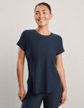 Woman wearing a blue short sleeve t-shirt and leggings against a plain background.