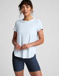 Woman wearing a light blue t-shirt and navy bike shorts on a plain background.