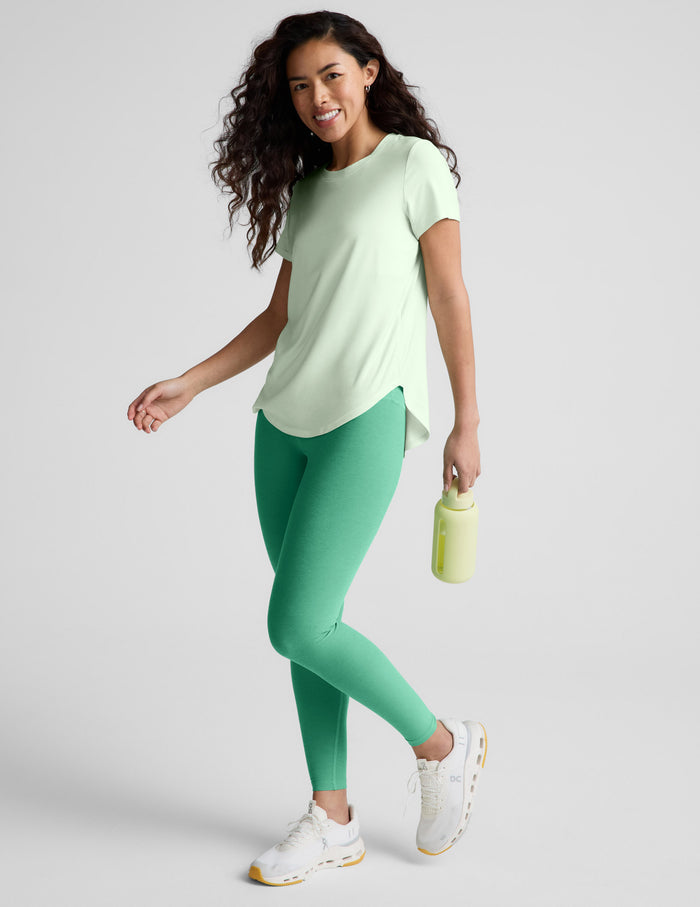 Woman wearing a light green t-shirt and green leggings on a white background.