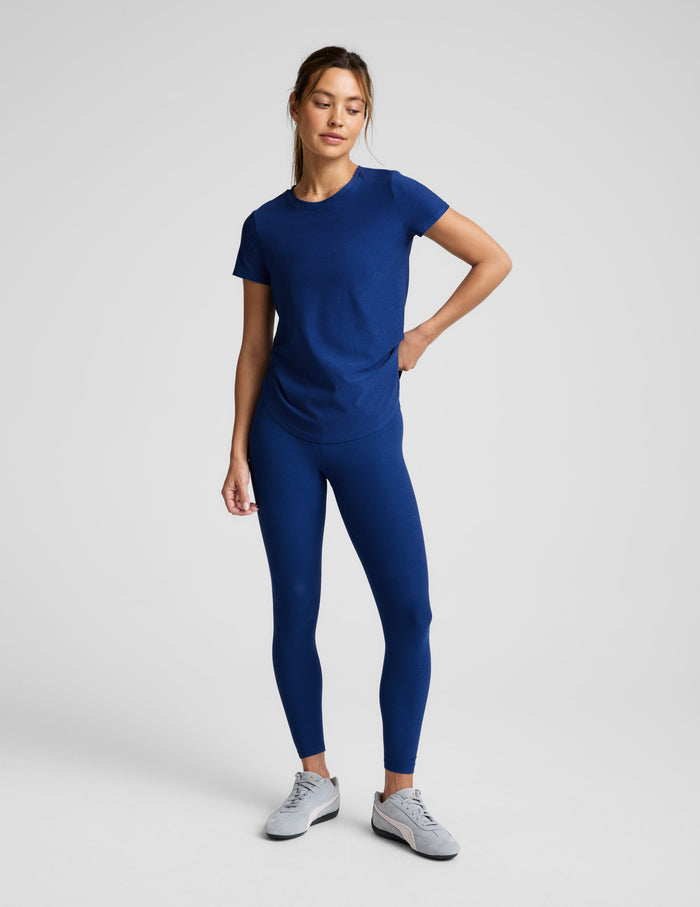 Woman wearing a blue t-shirt and leggings against a plain background.