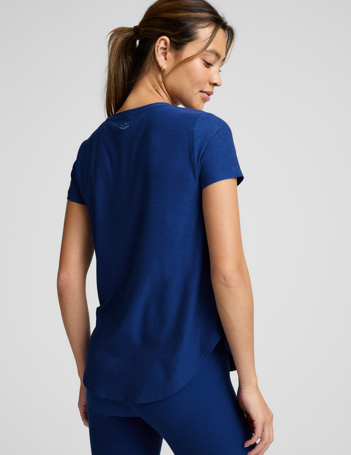 Woman wearing a blue t-shirt and leggings against a plain background.