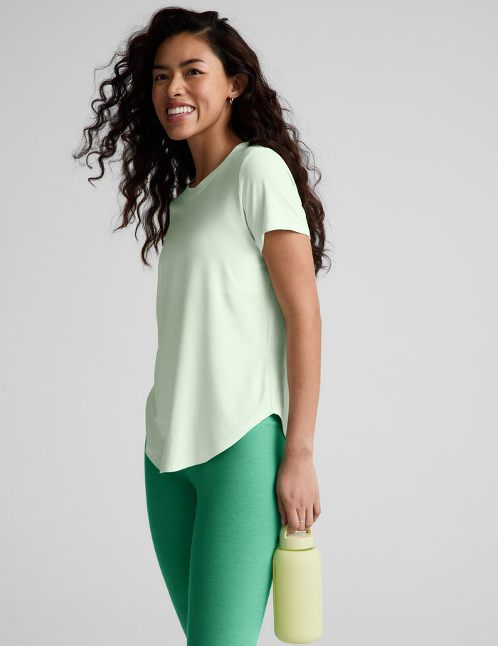 Woman wearing a light green t-shirt and green leggings on a white background.