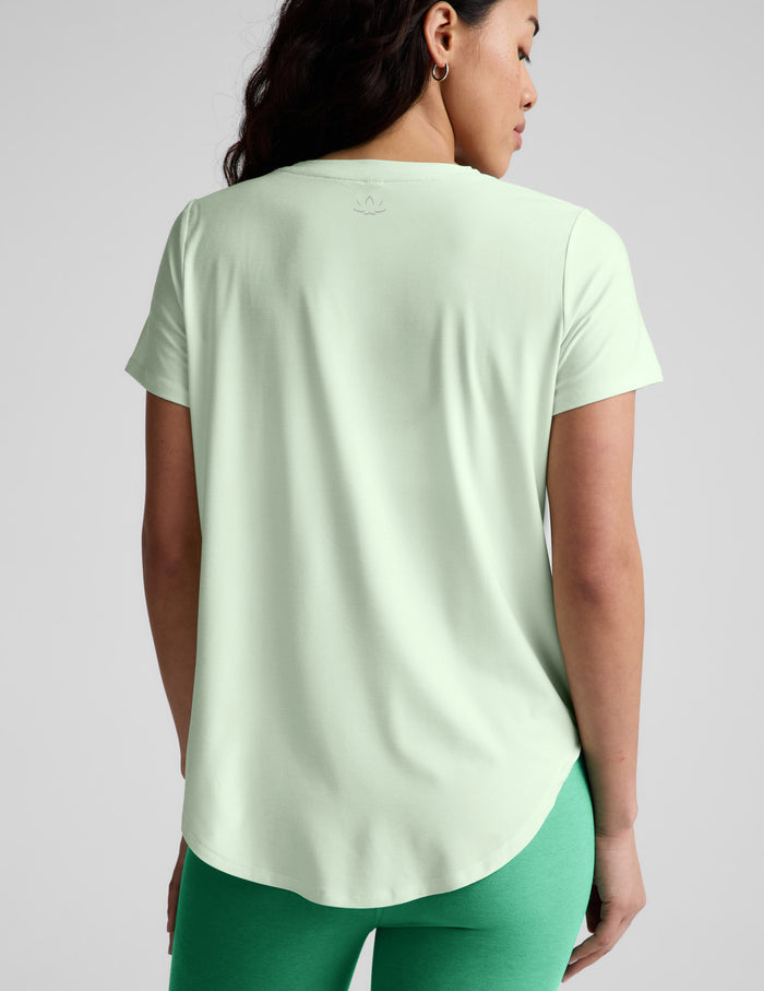 Woman wearing a light green t-shirt and green leggings on a white background.