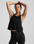 Woman wearing a black sleeveless cropped racerback tank and leggings against a light gray background.