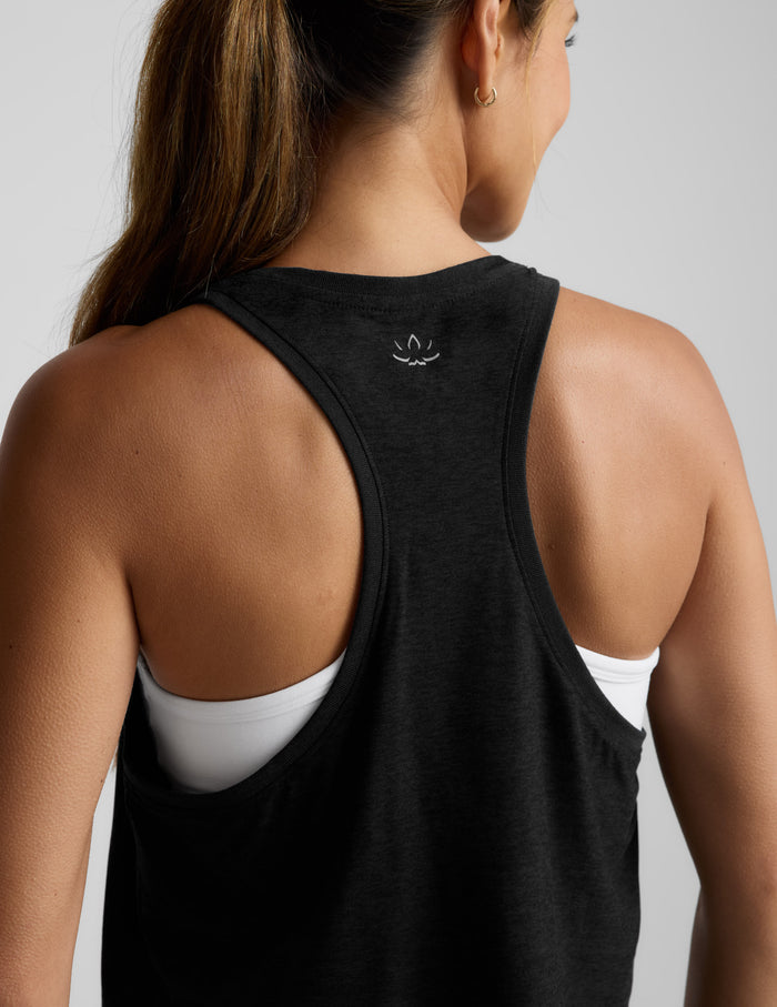 Woman wearing a black sleeveless cropped racerback tank and leggings against a light gray background.